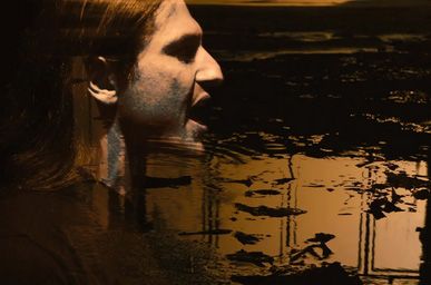 Close-up of a singer in profile in warm sepia tones from the IGNITE music video for The Butcher In Me